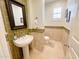 Stylish powder room featuring a pedestal sink, tiled walls, and a framed mirror at 3912 E Williams Dr, Phoenix, AZ 85050