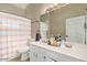 Bright bathroom featuring a white double sink vanity, framed mirror, and a shower with a striped curtain at 3957 E Adobe St, Mesa, AZ 85205