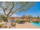 Outdoor kitchen with a built-in grill, sink, and seating area overlooking a pool and desert scenery at 40607 N Candlewyck Ln, Phoenix, AZ 85086