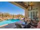 Covered patio with ceiling fan overlooks the pool, spa, and desert landscape, inviting outdoor relaxation at 40607 N Candlewyck Ln, Phoenix, AZ 85086