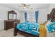 Bright bedroom featuring neutral carpet, ceiling fan, dresser and blue patterned bedding at 43556 W Colby Dr, Maricopa, AZ 85138