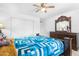 Bright bedroom with a ceiling fan, blue patterned bedding, and dresser with mirror at 43556 W Colby Dr, Maricopa, AZ 85138