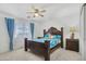 Bright bedroom with a ceiling fan, blue patterned bedding, and decorative dark wood frame bed at 43556 W Colby Dr, Maricopa, AZ 85138