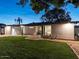 View of the back exterior, showcasing the flat roof design, neutral color scheme, and well-kept lawn at 5807 N 18Th St, Phoenix, AZ 85016