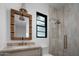 Bathroom featuring a shower with glass doors, a window, and a sink with a stone countertop and a decorative woven mirror at 6312 E Calle Del Paisano --, Scottsdale, AZ 85251