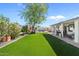 Landscaped backyard with artificial turf, mature trees, covered patio, outdoor seating and a playhouse at 6440 E Jean Dr, Scottsdale, AZ 85254