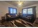 Cozy living room featuring a dark brown leather sofa, wood flooring, and ample natural light from the windows at 650 N Hawes Rd # 3827, Mesa, AZ 85207