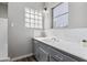 Bathroom vanity with gray cabinets and a tile backsplash underneath a bright window at 713 E Eason Ave, Buckeye, AZ 85326