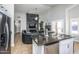 Modern kitchen flows to living area with a large island and black stone fireplace at 7365 W Via Del Sol Dr, Glendale, AZ 85310