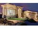 Exterior shot of home with decorative rock landscaping, arched entry and 3-car garage at twilight at 7952 E Teton Cir, Mesa, AZ 85207