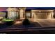 Nighttime view of the home's exterior with a well-manicured front yard and three-car garage at 7952 E Teton Cir, Mesa, AZ 85207