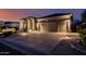 Exterior shot of home with a long driveway leading to a three-car garage at twilight at 7952 E Teton Cir, Mesa, AZ 85207