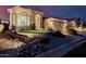 Exterior shot of home with decorative rock landscaping, arched entry and 3-car garage at twilight at 7952 E Teton Cir, Mesa, AZ 85207