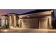 Exterior shot of home with a long driveway leading to a three-car garage at twilight at 7952 E Teton Cir, Mesa, AZ 85207