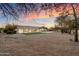 Expansive backyard with lush lawn, desert landscaping, a pool, and views of the home's exterior at dusk at 8254 E Juan Tabo Rd, Scottsdale, AZ 85255