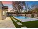 Backyard pool with stone surround, artificial turf, and desert landscaping against a vibrant sunset sky at 8254 E Juan Tabo Rd, Scottsdale, AZ 85255