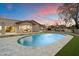 Beautiful pool with stone surround, lush lawn, and the home's exterior in the background against a colorful sky at 8254 E Juan Tabo Rd, Scottsdale, AZ 85255