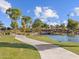 Concrete path by a lake leads to a bridge and playground in a scenic community park at 8560 W Trenton Ct, Florence, AZ 85132