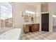 Bright bathroom with a large window, soaking tub, and double vanity at 11628 S Warcloud Ct, Phoenix, AZ 85044