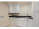 Convenient laundry room featuring white cabinets, dark counter tops, and wallpaper at 11628 S Warcloud Ct, Phoenix, AZ 85044