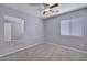 A simple bedroom with a ceiling fan, a large mirror, neutral carpet, and a window with blinds at 11954 W Melinda Ln, Sun City, AZ 85373