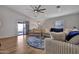 Bright living room with hardwood floors, a plush sectional sofa, sliding glass doors, and a ceiling fan at 11954 W Melinda Ln, Sun City, AZ 85373