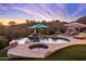 A beautiful pool and spa with rock waterfall feature, set against a stunning sunset sky at 12026 N 138Th St, Scottsdale, AZ 85259