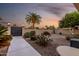 Desert landscaped backyard with walkway, palm trees, and block wall with gate under dusk sky at 12539 W Paintbrush Dr, Sun City West, AZ 85375