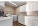 Clean laundry room with white cabinets, marble countertops, washer, and dryer at 12539 W Paintbrush Dr, Sun City West, AZ 85375