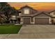 Two-story home featuring a well-manicured lawn and a three-car garage under a vivid sunset sky at 13566 N 93Rd Pl, Scottsdale, AZ 85260