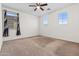 A bright bedroom with neutral carpet, white walls, ceiling fan, and two windows at 21195 W Coronado Rd, Buckeye, AZ 85396