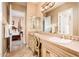 Bathroom featuring a double sink vanity, decorative mirror, and access to bedroom at 22020 N San Ramon Dr, Sun City West, AZ 85375