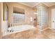 Bright bathroom featuring a soaking tub, glass block window, and travertine tile flooring at 22020 N San Ramon Dr, Sun City West, AZ 85375