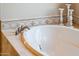 Close-up of a white soaking bathtub with elegant faucet and tile surround at 22020 N San Ramon Dr, Sun City West, AZ 85375