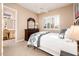 Bedroom featuring a wrought iron bed, neutral walls, plantation shutters, and access to bathroom at 22020 N San Ramon Dr, Sun City West, AZ 85375