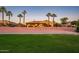 Single-story home with desert landscaping, palm trees, and backyard patio visible at sunset at 22020 N San Ramon Dr, Sun City West, AZ 85375