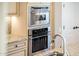 Close-up of modern stainless steel built-in microwave and oven next to white cabinetry at 22020 N San Ramon Dr, Sun City West, AZ 85375