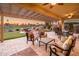 Inviting covered outdoor patio with stone flooring, overlooking the putting green and golf course at sunset at 22020 N San Ramon Dr, Sun City West, AZ 85375