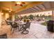 Covered outdoor patio with travertine flooring, dining set, seating area, and views of the golf course at 22020 N San Ramon Dr, Sun City West, AZ 85375