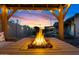 Close-up of a modern fire pit with flames, surrounded by seating in a landscaped backyard setting with warm lighting at 2747 S Brooks --, Mesa, AZ 85202