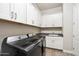 Well-lit laundry room features sleek front load machines, sink, and ample storage in white shaker cabinets at 4097 E Tonto Pl, Chandler, AZ 85249