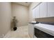 Bright laundry room with white cabinets, light tile flooring, and modern washer and dryer at 41413 N Club Pointe Dr, Anthem, AZ 85086