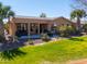 Spacious backyard with green grass, mature palms, and covered patio seating area at 42432 W North Star Dr, Maricopa, AZ 85138