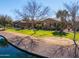 Backyard view showcasing path, lake, desert landscaping, grassy lawn, and homes in distance at 42432 W North Star Dr, Maricopa, AZ 85138