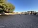 Expansive gravel backyard featuring mature shade tree, playground and pergola with lots of room for entertaining at 4511 S 181St Ave, Goodyear, AZ 85338