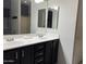 Primary bathroom features a double sink vanity with black cabinets, large mirrors, and tile flooring at 4511 S 181St Ave, Goodyear, AZ 85338