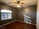 An empty bedroom with a ceiling fan and wood-look floors basks in natural light from the window at 4511 S 181St Ave, Goodyear, AZ 85338