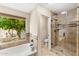 Bathroom featuring a walk-in glass shower, soaking tub, and a view of the backyard at 5024 E Le Marche Ave, Scottsdale, AZ 85254