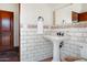 A bathroom featuring a pedestal sink and decorative brick-style wall tile at 5567 E Mcdonald Dr, Paradise Valley, AZ 85253