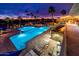 Beautifully lit outdoor pool and deck area with palm trees at dusk with chairs and tables nearby at 6177 S Sawgrass Dr, Chandler, AZ 85249